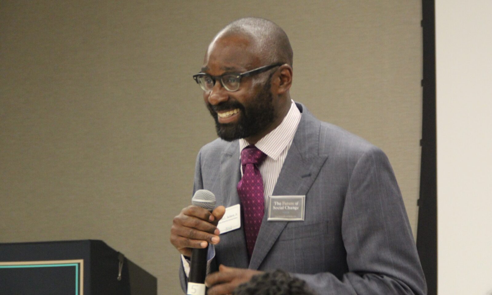 Dean Jackson standing with microphone while presenting on his vision for the School.