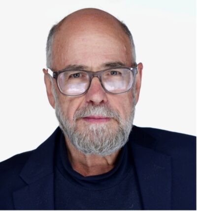 A closeup portrait of a man with squared glasses and gray facial hair