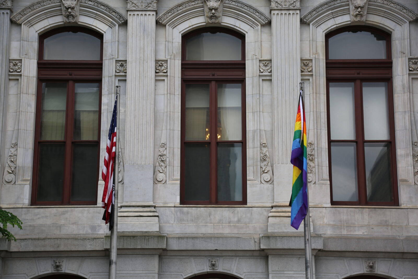 U.S. flag and the new LGBTQ flag, side by side in front of Philadelphia CIty Hall