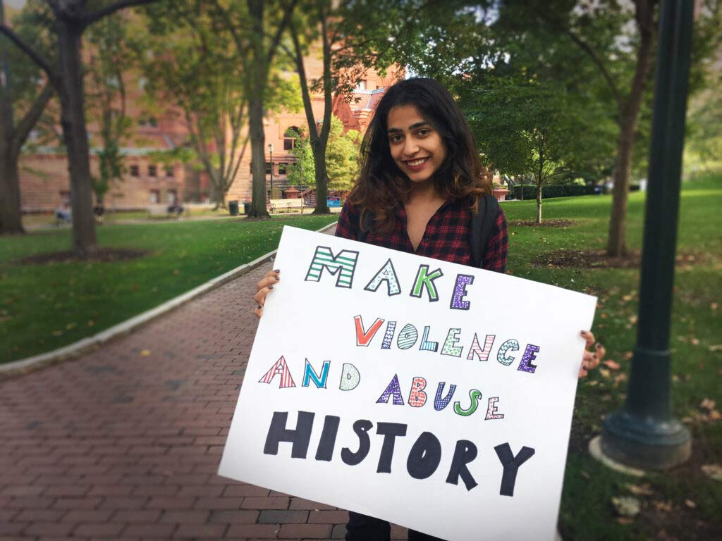 Student holds sign on Locust Walk