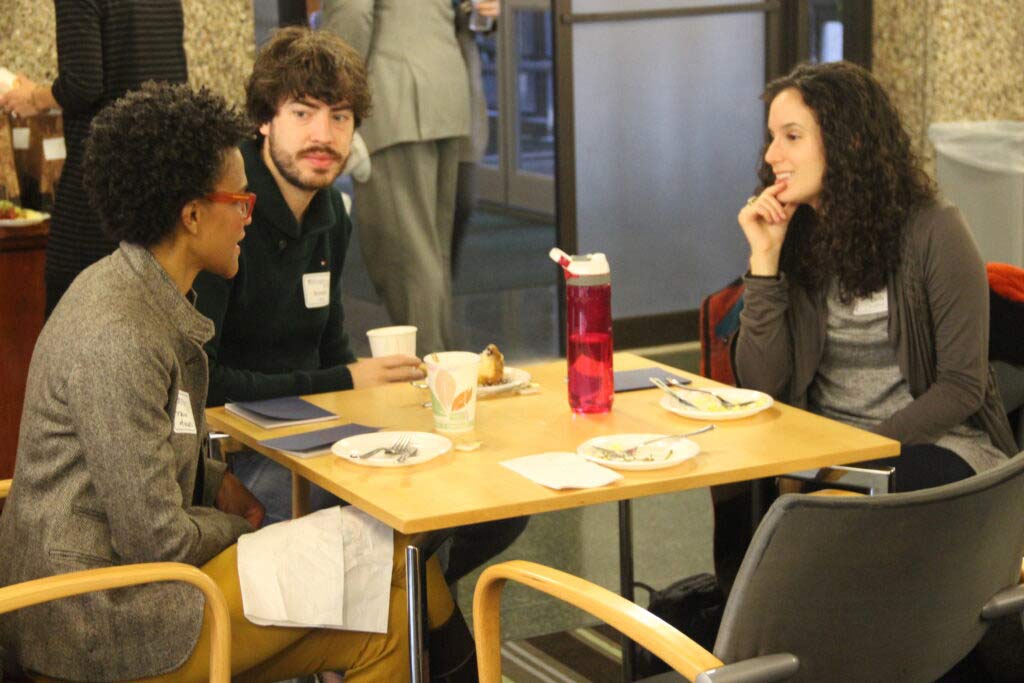 three alumni sit at table and chat