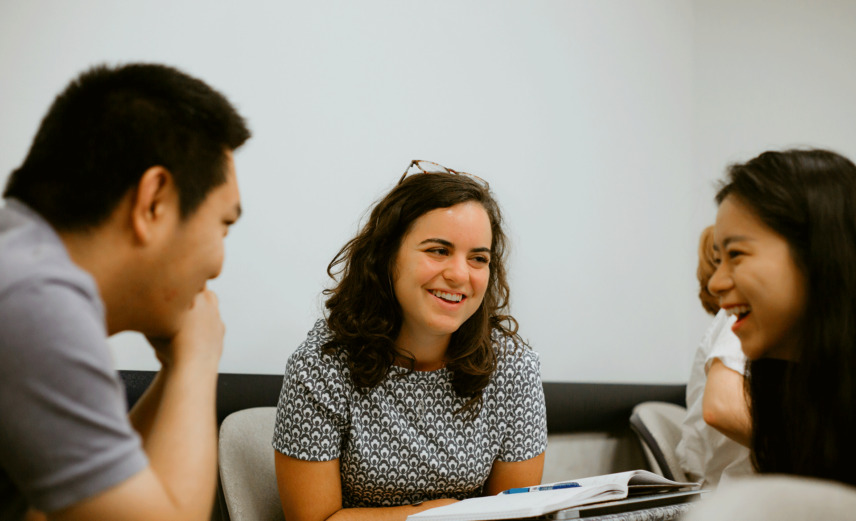 Three students sitting around a table smiling