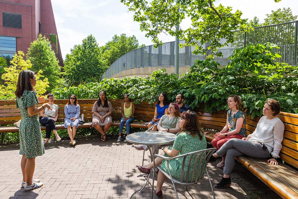 Group of students sitting on benches outside listening to a presentation