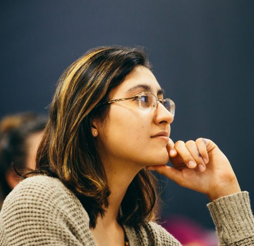 Female student with chin in left hand listening intently