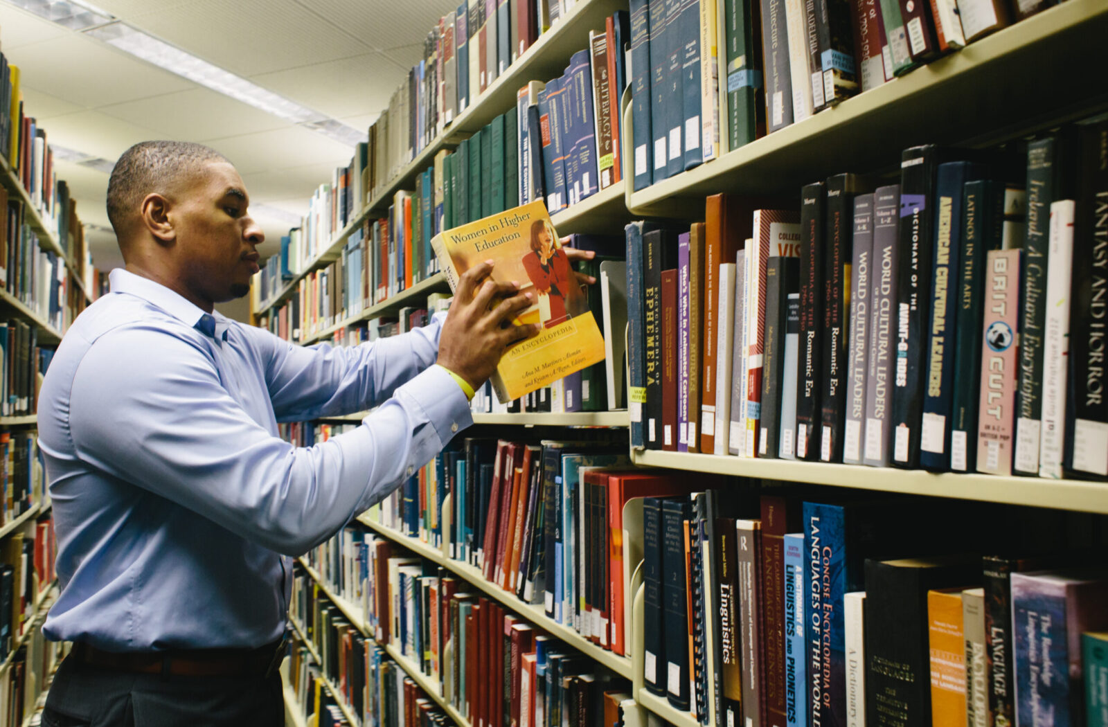 Male placing book on library shelf