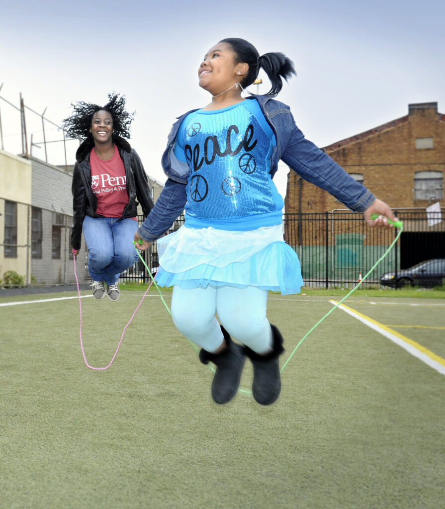 SP2 student and a young girl jump rope outside