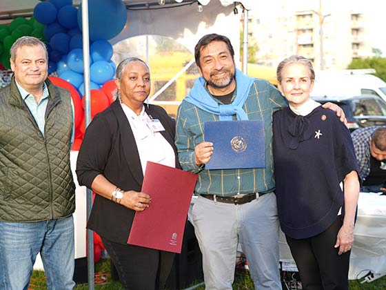 Four people stand in line posing & smiling