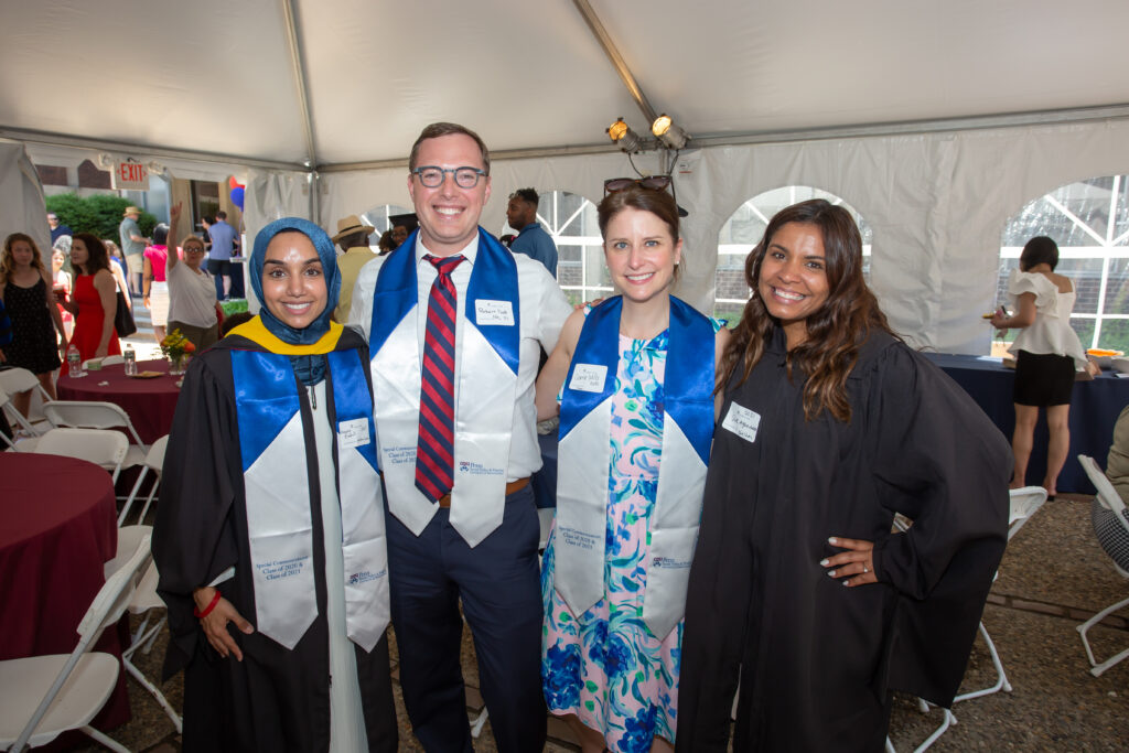 Four alumni pose for a photo in the tent