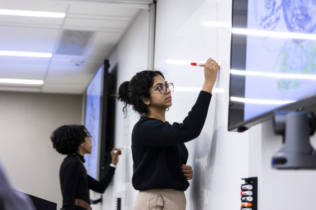 Student uses a marker to write on a whiteboard