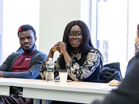 Mayowa Fageyinbo speaks at a classroom table