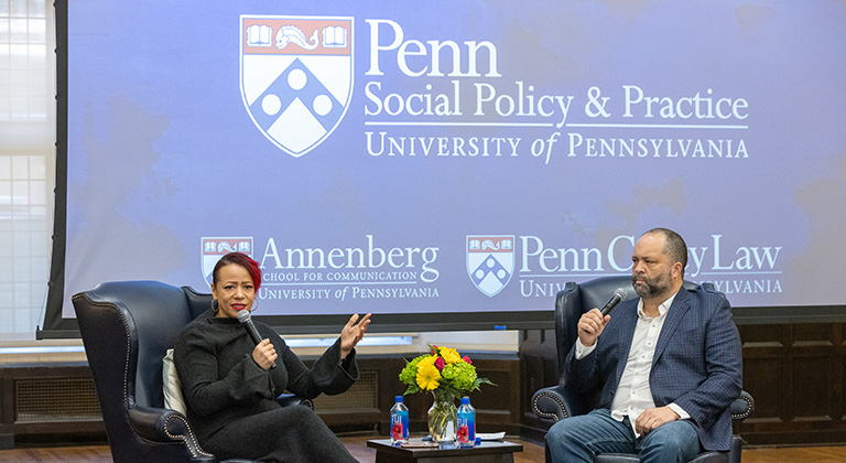 Nikole Hannah-Jones and Ben Jealous sit onstage. A blue screen behind them shows the logos of Penn's School of Social Policy & Practice, the Annenberg School, and Penn Carey Law.