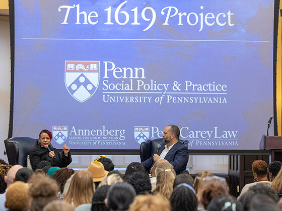 Nikole Hannah-Jones and Ben Jealous sit onstage before an audience. A blue screen behind them says 