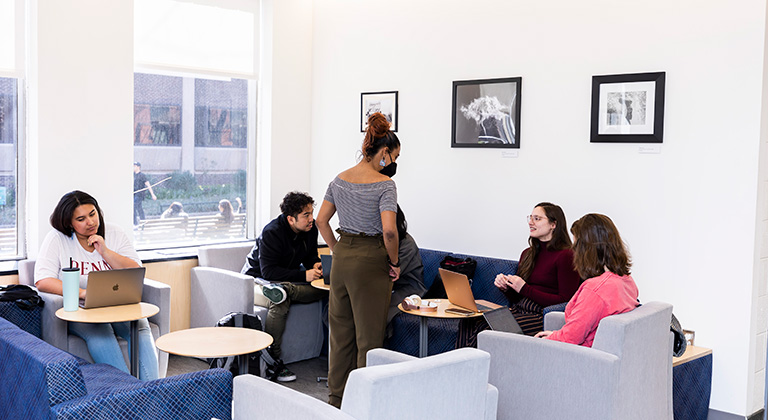 Students sit and converse or work on laptops in the Caster lobby