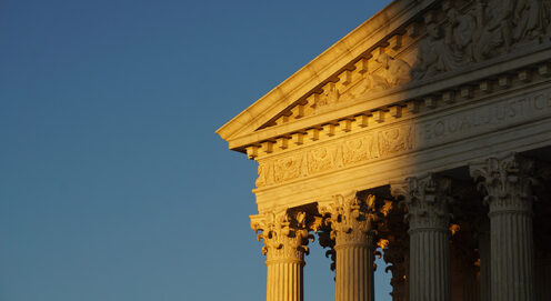 The light of sunset shines on a portion of the Supreme Court building and columns