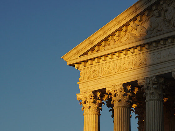 The light of sunset shines on a portion of the Supreme Court building and columns