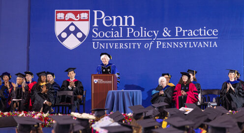 Dean Bachman and SP2's faculty appear onstage at Commencement with the Penn Social Policy & Practice on a blue backdrop behind them