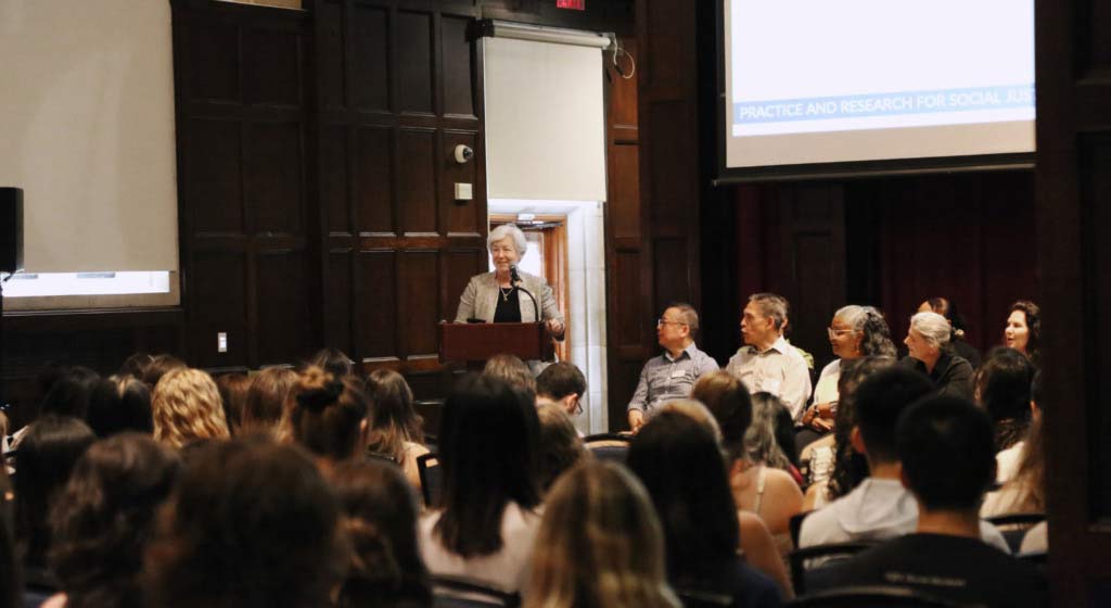 Dean Bachman stands at a podium speaking to the crowd for Convocation.