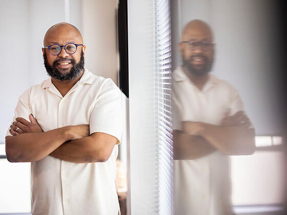 Desmond Patton stands beside a reflection of himself in a window