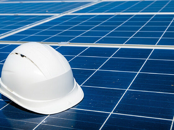 A white hard hat sits on a blue solar panel