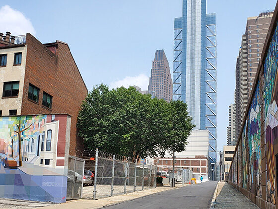 A Philadelphia neighborhood street with murals on each side and a skyscraper ahead