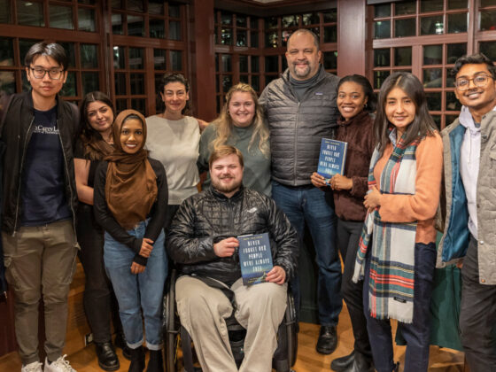 Leading Social Change instructors Ariel Schwartz and Ben Jealous pose for a photo with students, some holding up Ben's book titled 