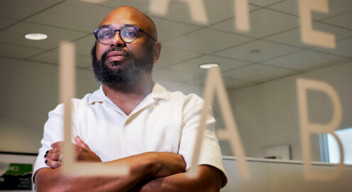 Dr. Patton stands with arms folded behind a window with the word 