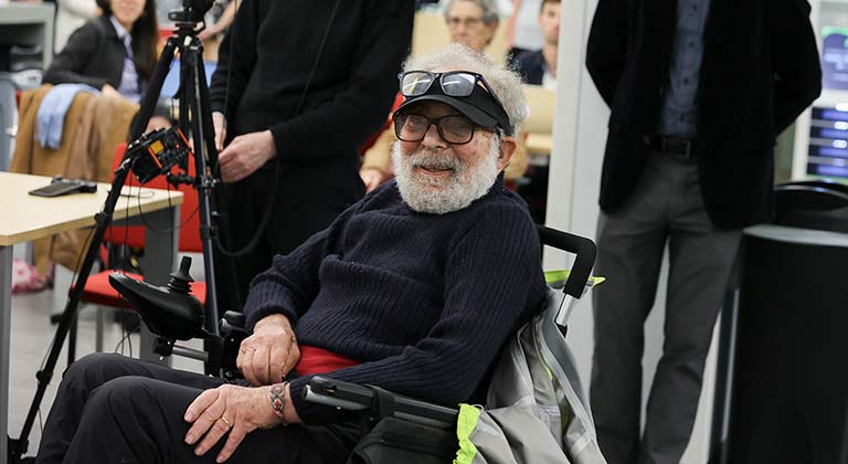 An attendee in a wheelchair smiles at the camera.