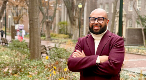 Desmond Patton stands beside Locust Walk, arms folded