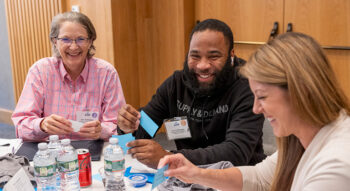 Three people sit together smiling at a round table