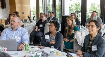 Attendees sit at round tables at an event