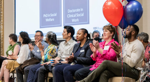 A photo of faculty seated in front a powerpoint presentation at SP2 2024 Convocation, red balloons in the foreground