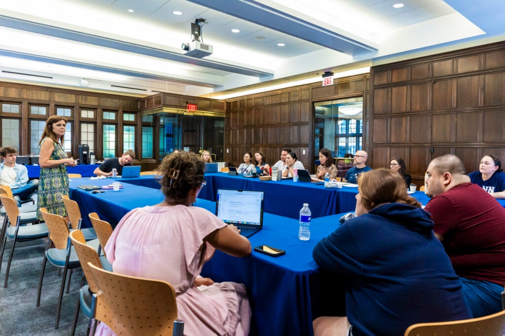 A group of students listening to a faculty member discuss the doctorate program, at a U shaped table setting